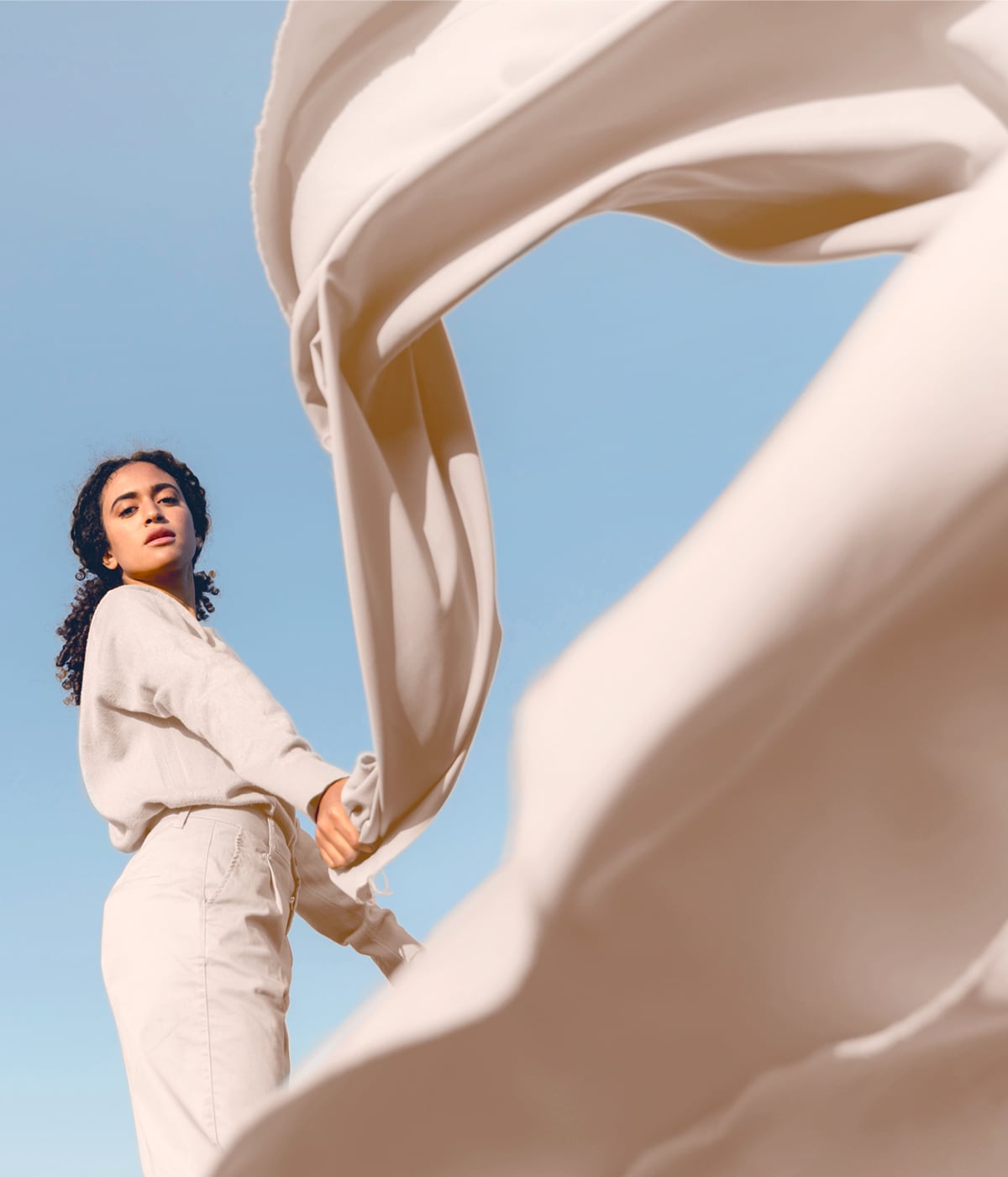 Donna che solleva un tessuto leggero, espressione della moda responsabile. Grazie alla tecnologia RFID di Temera, ogni materiale è tracciato per supportare