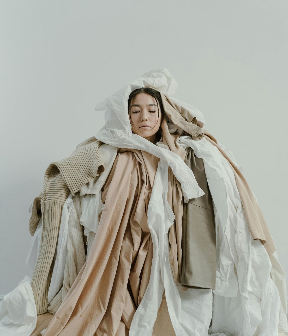 Donna circondata da una cascata di abiti, simbolo di un impegno contro lo spreco nella moda. Grazie alla tecnologia RFID di Temera, ogni capo è tracciato d